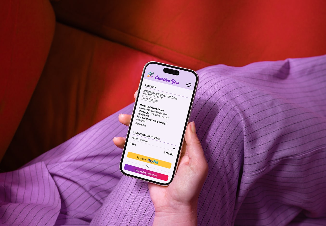 Person holding a smartphone; the screen shows a digital shopping cart with a course registration.
