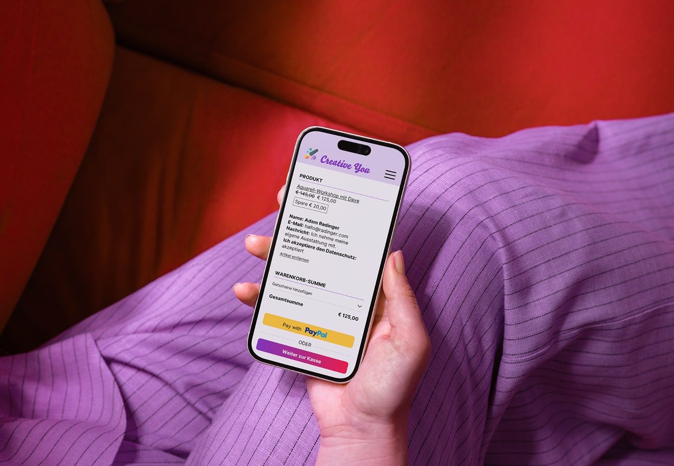 Person h&auml;lt ein Smartphone; auf dem Bildschirm ein digitaler Warenkorb mit einer Kursanmeldung.