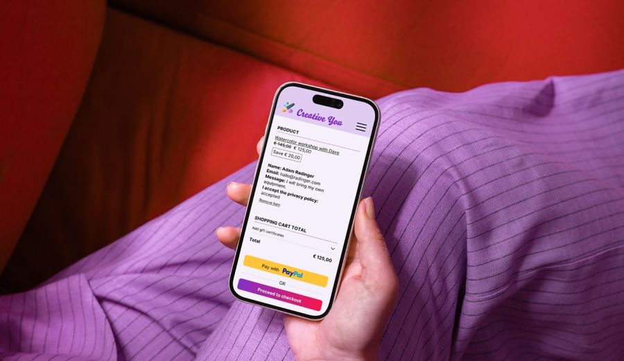 Person holding a smartphone; the screen shows a digital shopping cart with a course registration.