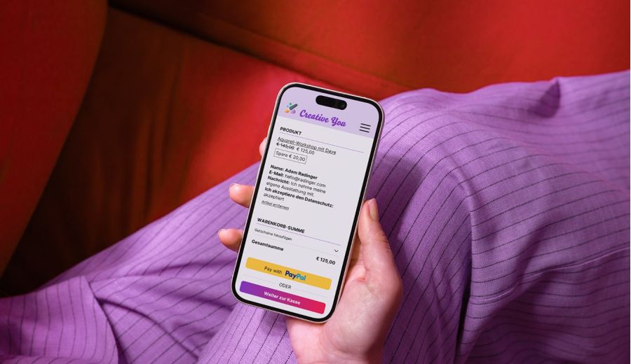 Person h&auml;lt ein Smartphone; auf dem Bildschirm ein digitaler Warenkorb mit einer Kursanmeldung.